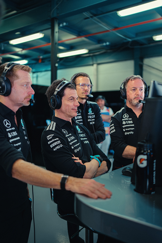 Formula 1 team members watching the race in the pit lane.